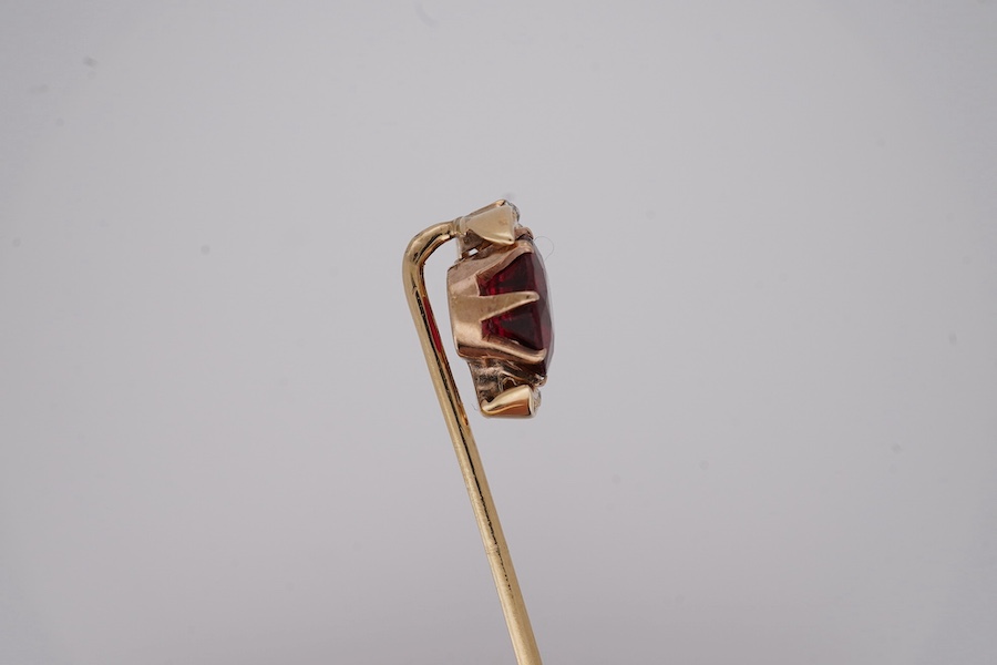 An early to mid 20th century yellow metal and single stone garnet topped doublet set stick pin, with diamond set crescent border, 61mm, gross weight 2.9 grams. Condition - fair to good